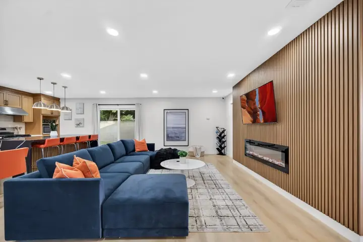 Open living room with a large sectional sofa, fireplace and adjoining kitchen